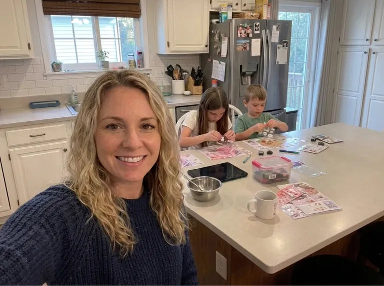 A mother with two children enjoying a screen-free sticker activity together at the kitchen island